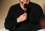Linus Torvalds speaking into a microphone at a Linux conference