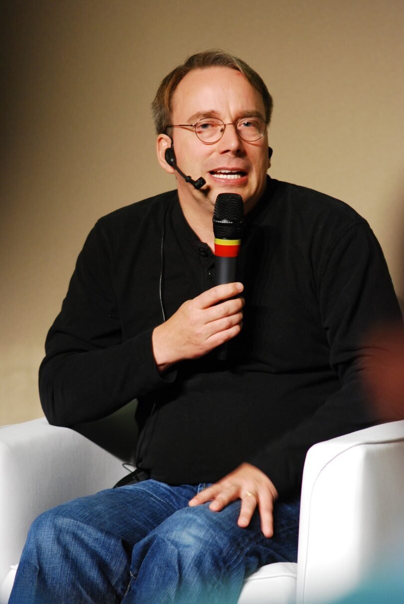 Linus Torvalds speaking into a microphone at a Linux conference